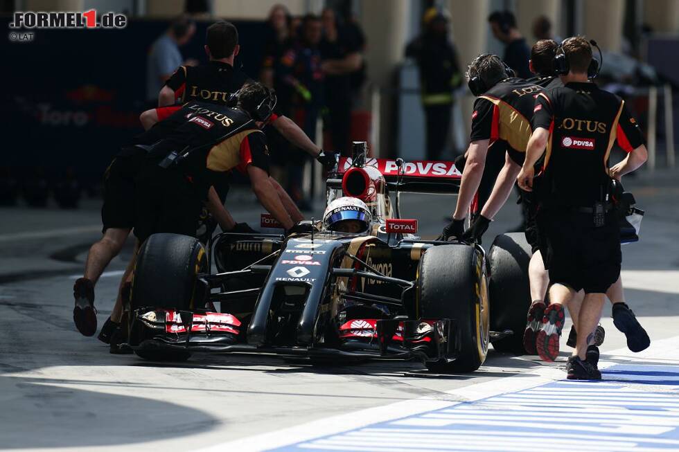 Foto zur News: Romain Grosjean (Lotus) wird von den Mechanikern in die Box zurückgeschoben.