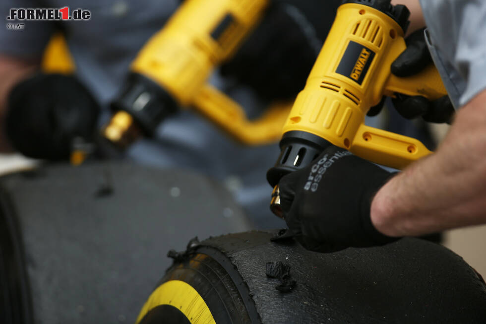 Foto zur News: Pirelli-Mechaniker schaben Gummi von den Laufflächen und verwenden dafür eine Hitzepistole