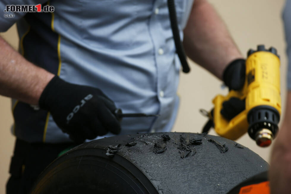 Foto zur News: Pirelli-Mechaniker schaben Gummi von den Laufflächen und verwenden dafür eine Hitzepistole