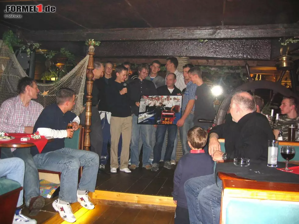 Foto zur News: Vettel überreicht das signierte Bild bei der Weihnachtsfeier im Dezember 2004 an seine Crew.
