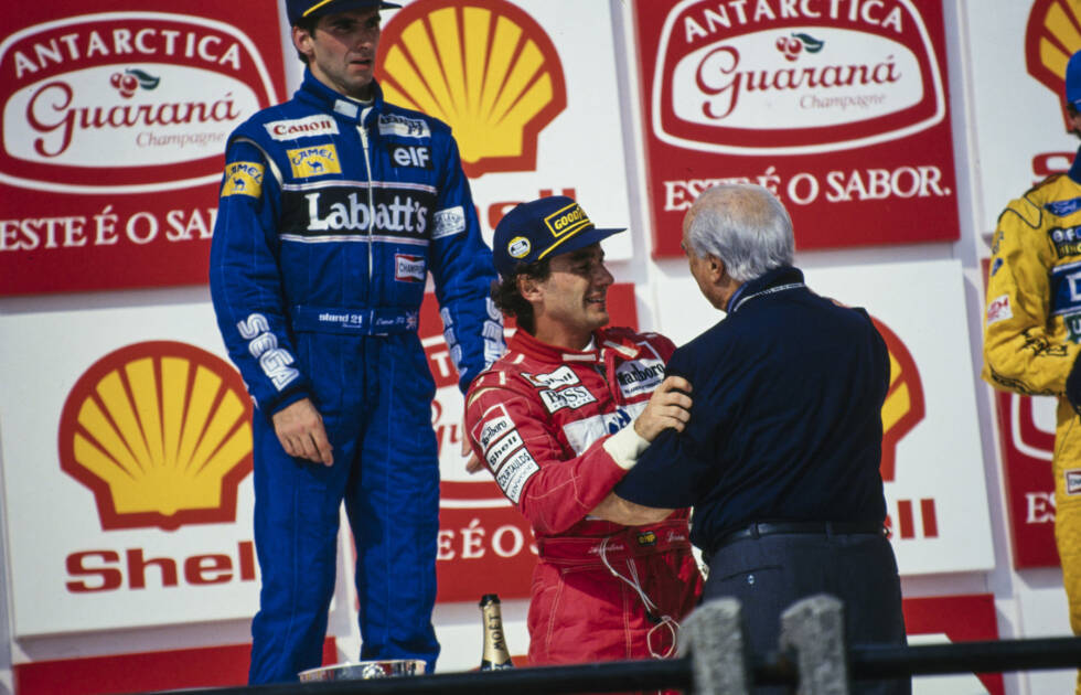 Foto zur News: Umarmung zweier Formel-1-Legenden. 1993 kommt es beim Grand Prix von Brasilien zu einem emotionalen Moment, als Juan Manuel Fangio Ayrton Senna den Siegerpokal überreicht.