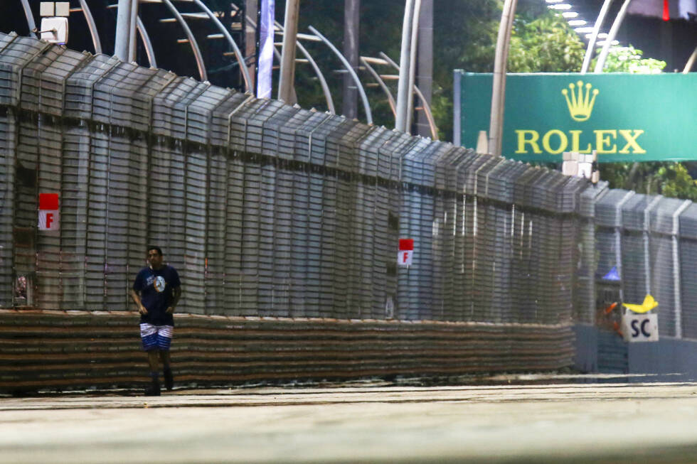 Foto zur News: Platz 6: Der Flitzer von Singapur - &quot;Da ist ein Mann auf der Strecke!&quot; Nein, Sebastian Vettel hat beim Großen Preis von Singapur keine Halluzinationen. In der 36. Runde des Rennens spaziert tatsächlich ein Zuschauer mitten über die Strecke. Wie sich später herausstellt, möchte der Mann mit seinem Smartphone wohl ein paar ganz besonders spektakuläre Aufnahmen machen. Dumm nur, dass die Aktion nicht nur brandgefährlich sondern auch illegal ist. Sicherheitskräfte schaffen es schließlich, den Mann unbeschadet wieder von der Strecke zu &quot;entfernen&quot;.