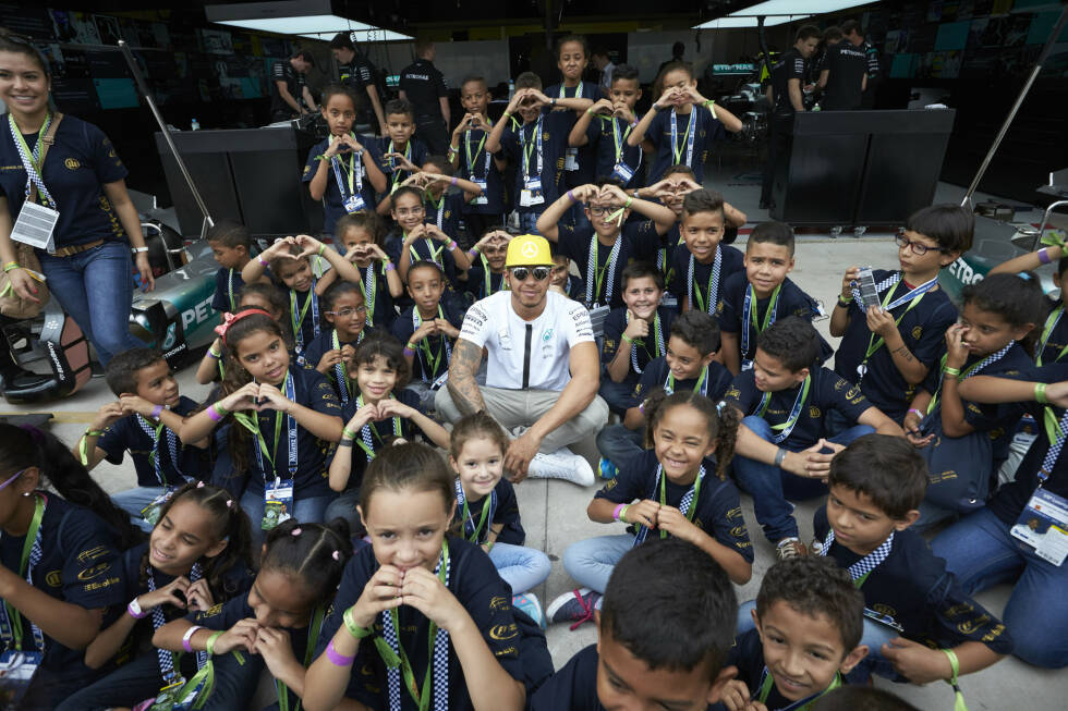 Foto zur News: Immerhin: Beim Fotoshooting mit den brasilianischen Kids wirkt Hamilton schon wieder deutlich fitter als beim Termin bei Madame Tussauds eine Woche zuvor. Und, sind wir mal ehrlich: Die Kinder in Sao Paulo sind auch etwas lebhafter als die Wachsfiguren in London.