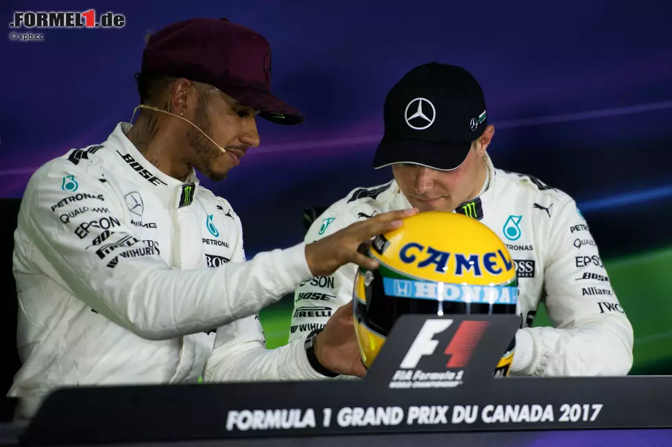 Foto zur News: Montreal ist für Hamilton ein besonderes Wochenende. Besonders wegen des Original-Senna-Helms, den er als Trophäe für die 65. Pole seiner Karriere erhält. Während der Top-3-Pressekonferenz zeigt er lieber Teamkollege Valtteri Bottas den Helm, als den Fragen der Journalisten zu lauschen.