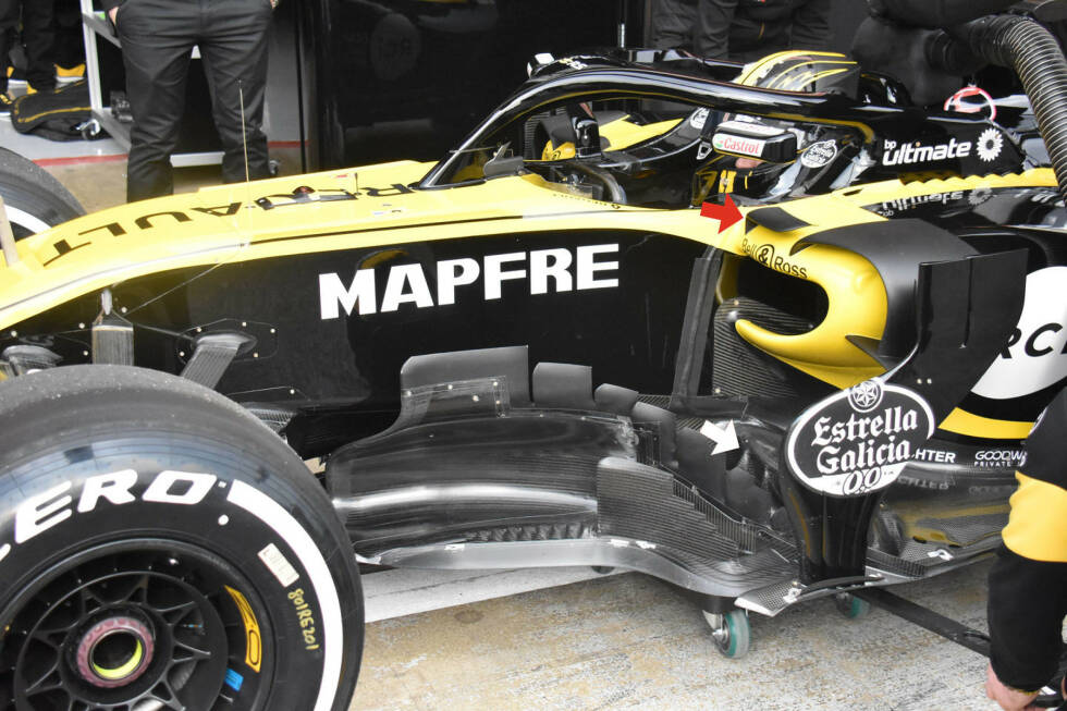 Foto zur News: Für den ersten Barcelona-Test hat Renault seitlich des Cockpits einen waagrechten Zusatzflügel installiert (roter Pfeil), der bei der Präsentation noch nicht zu sehen gewesen war. Das Team setzt nun ebenfalls auf eine mit Einschnitten versehene Vorderkante am Unterboden (weißer Pfeil).