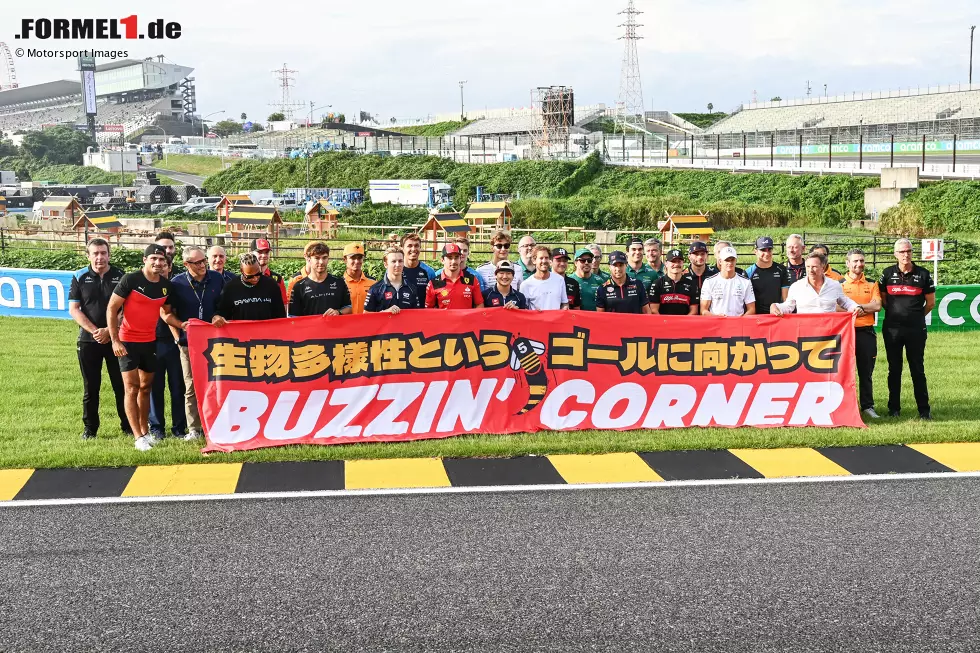 Foto zur News: &quot;Buzzin&#039; Corner&quot;: Sebastian Vettel und die Formel-1-Fahrer 2023 bei der Vorstellung des Insekten-Projekts von Vettel im Infield des Suzuka International Racing Course in Japan. Die schwarz-gelben Randsteine sind kein Zufall, sondern ...