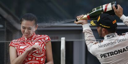 Foto zur News: Lewis Hamilton spritzt beim China Grand Prix 2015 Champagner auf ein Grid Girl