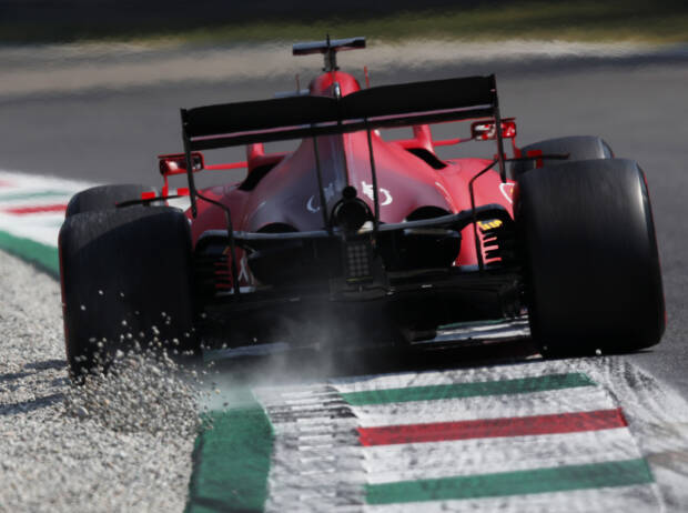 Heckansicht von Charles Leclerc (Ferrari), der beim Durchfahren einer Kurve in Monza 2021 über den Randstein Kieselsteine aufwirbelt