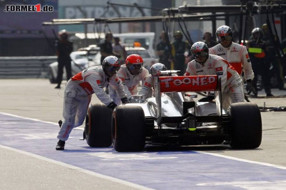 Foto zur News: Mechaniker schieben den McLaren von Jenson Button zurück nach einem fehlerhaften Boxenstopp beim Formel-1-Rennen in China 2013